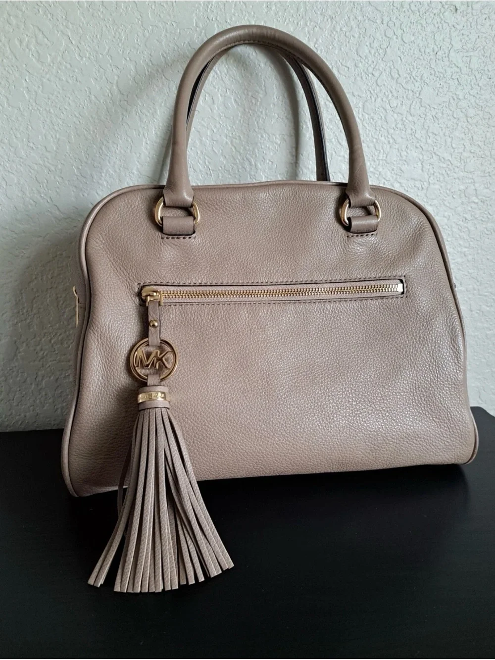 Michael Kors Knox Satchel featuring a prominent tassel and gold-tone hardware